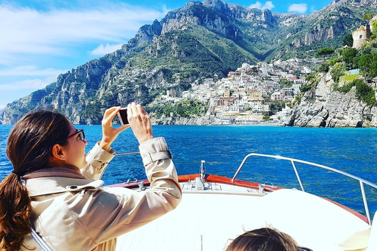 una dona fent una foto de la costa amalfitana en un vaixell