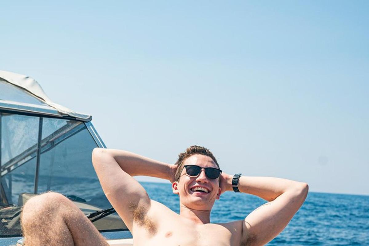 Un hombre con gafas de sol sentado en un barco en el agua.