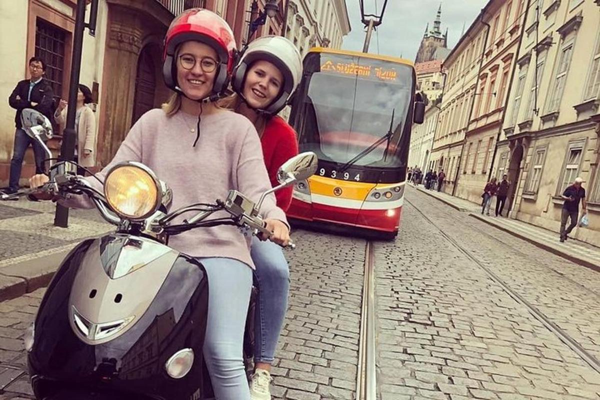 dues dones assegudes en un escúter davant d'un tramvia