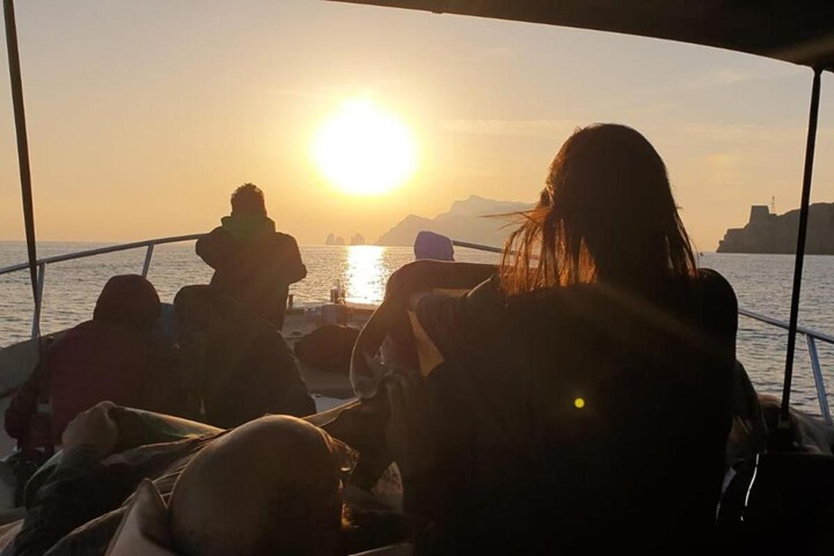 um grupo de pessoas sentadas em um barco assistindo ao pôr do sol