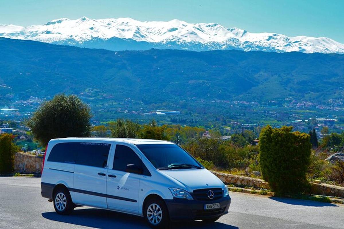 uma van branca estacionada em um estacionamento com montanhas cobertas de neve