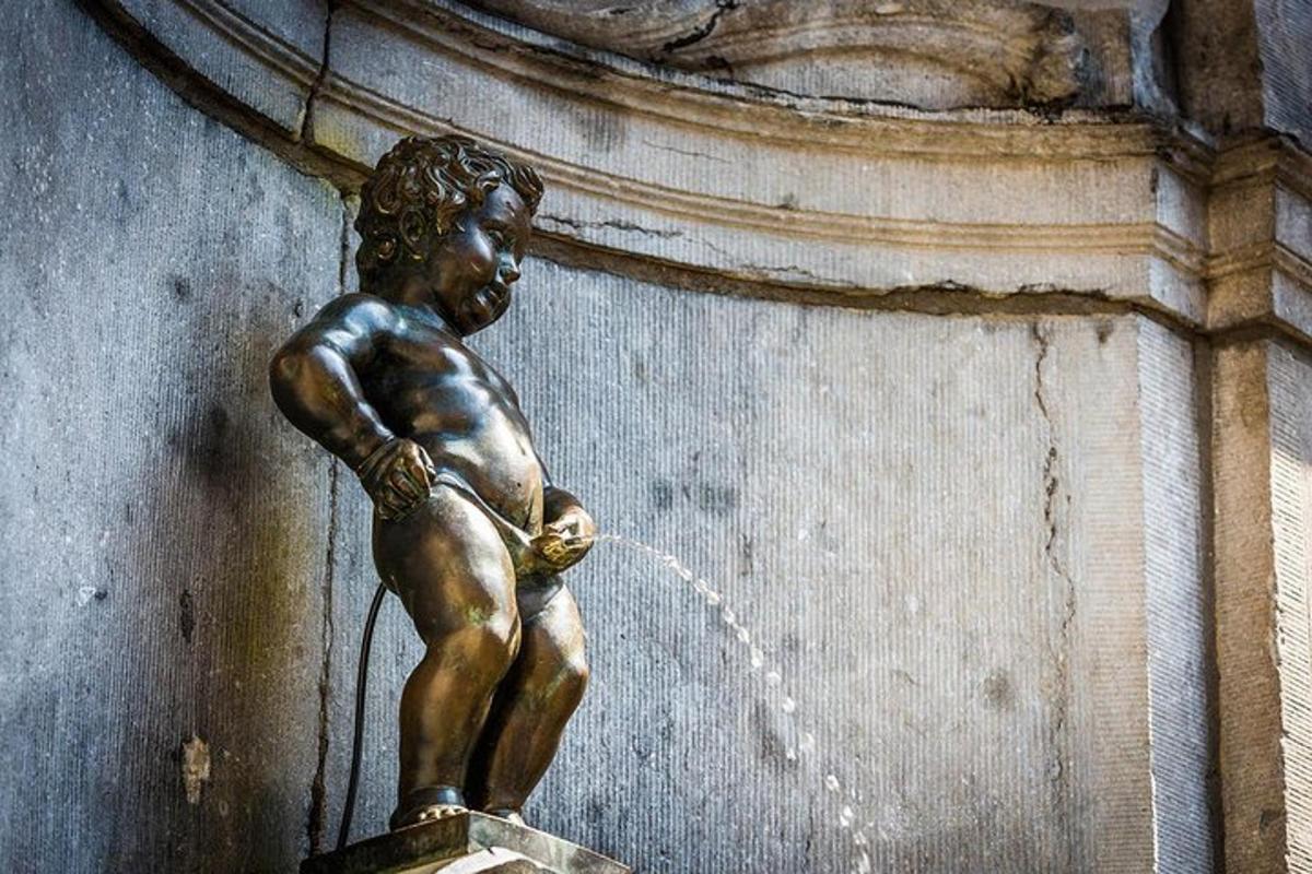 uma estátua de bronze de um menino bebendo de uma fonte