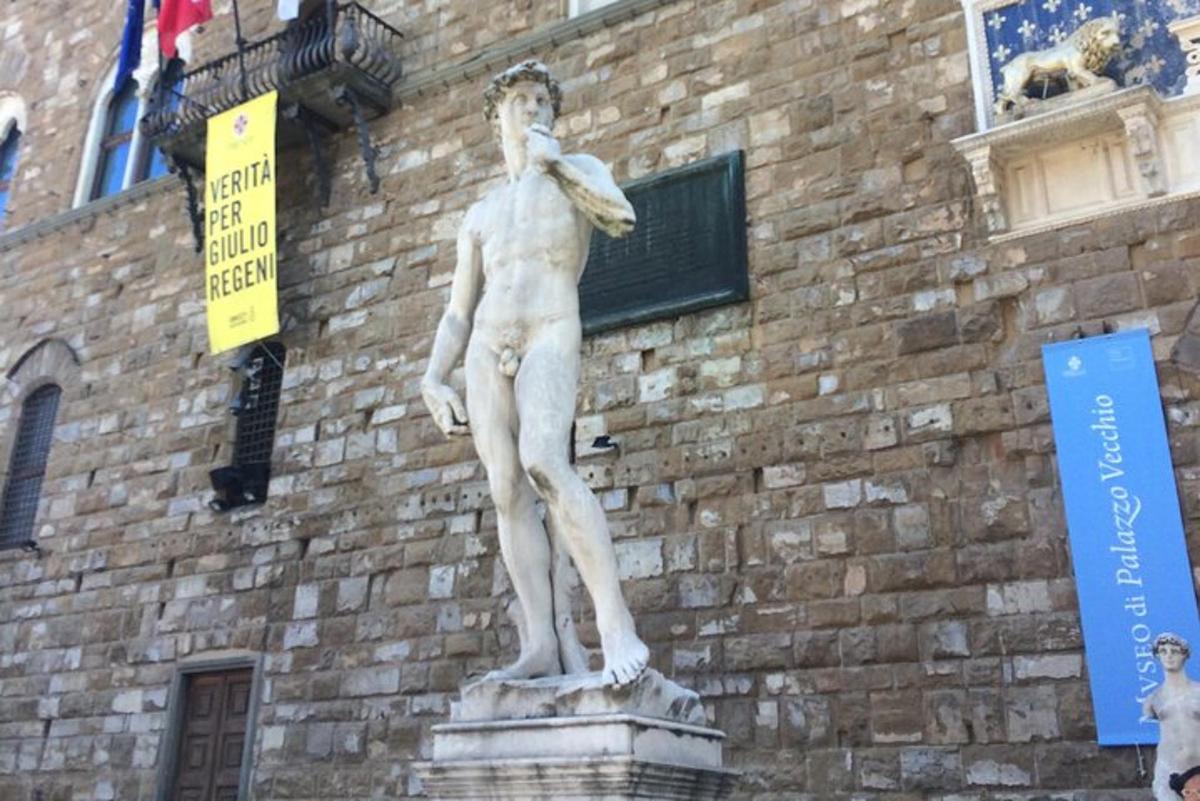 o statuie a unui bărbat care stă în fața unei clădiri