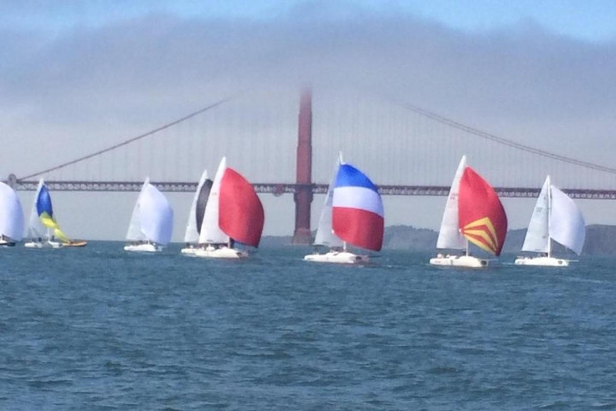 isang grupo ng mga sailboat sa tubig sa harap ng isang tulay