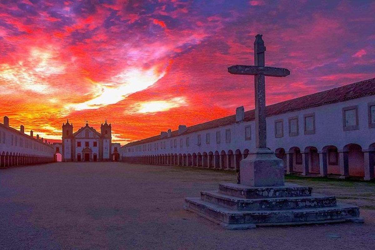 Una cruz frente a un edificio con una puesta de sol.