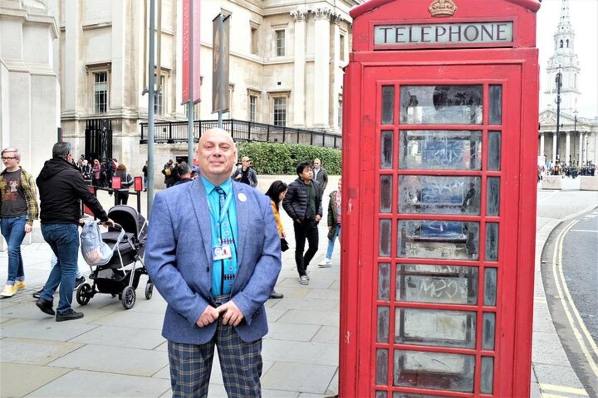 muž stojící vedle červené telefonní budky
