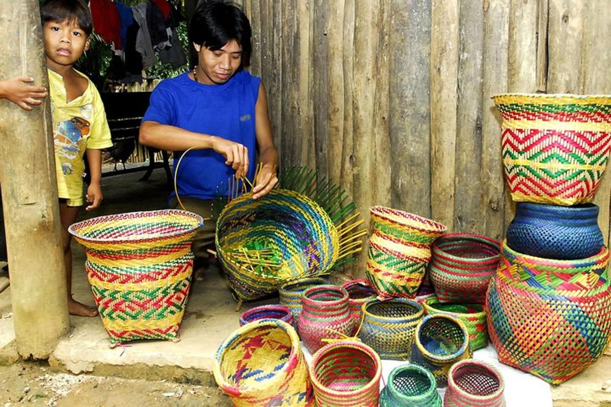 a man sitting next to a pile of colorful vases