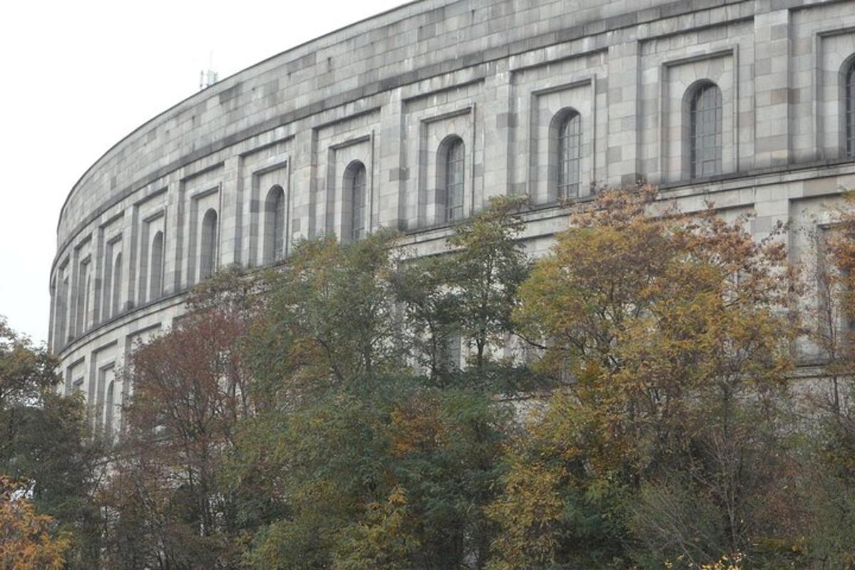 Un gran edificio de piedra con árboles delante.