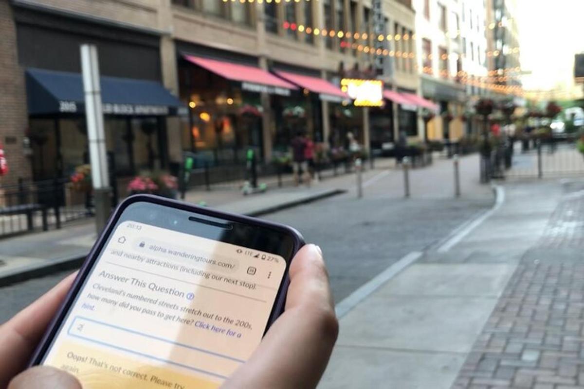 egy személy a kezében mobiltelefonnal az utca előtt
