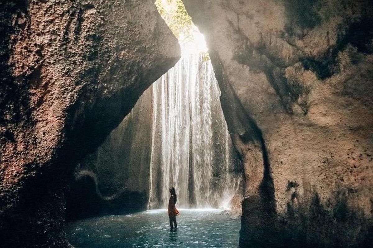 eine Person, die vor einem Wasserfall im Wasser steht