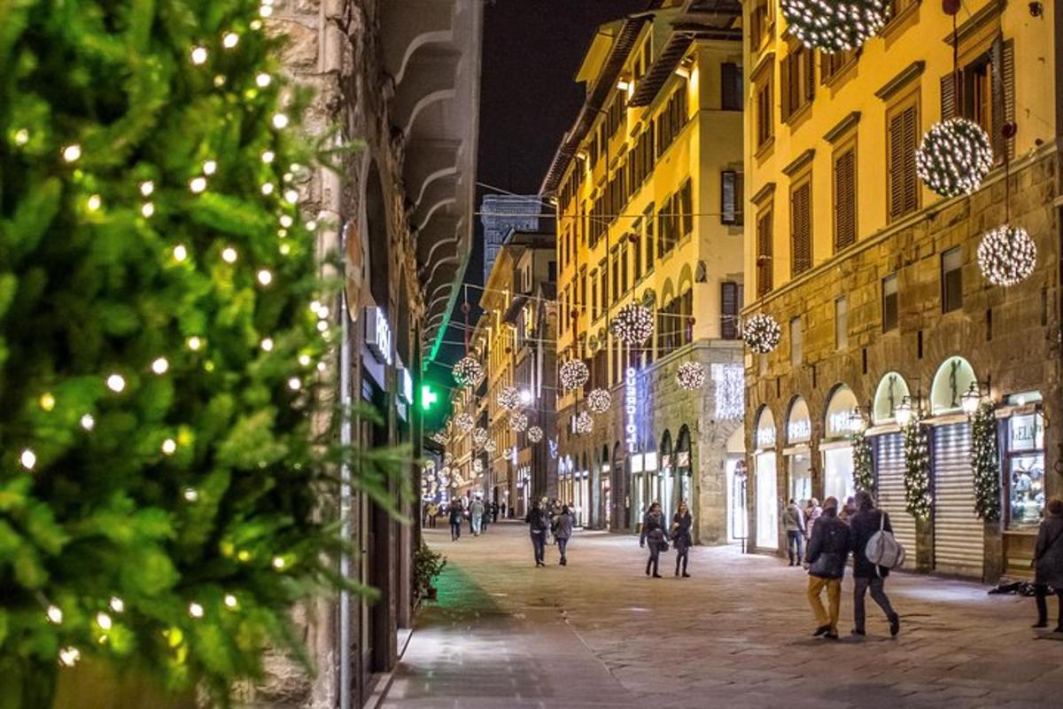 pessoas caminhando por uma rua com luzes de natal