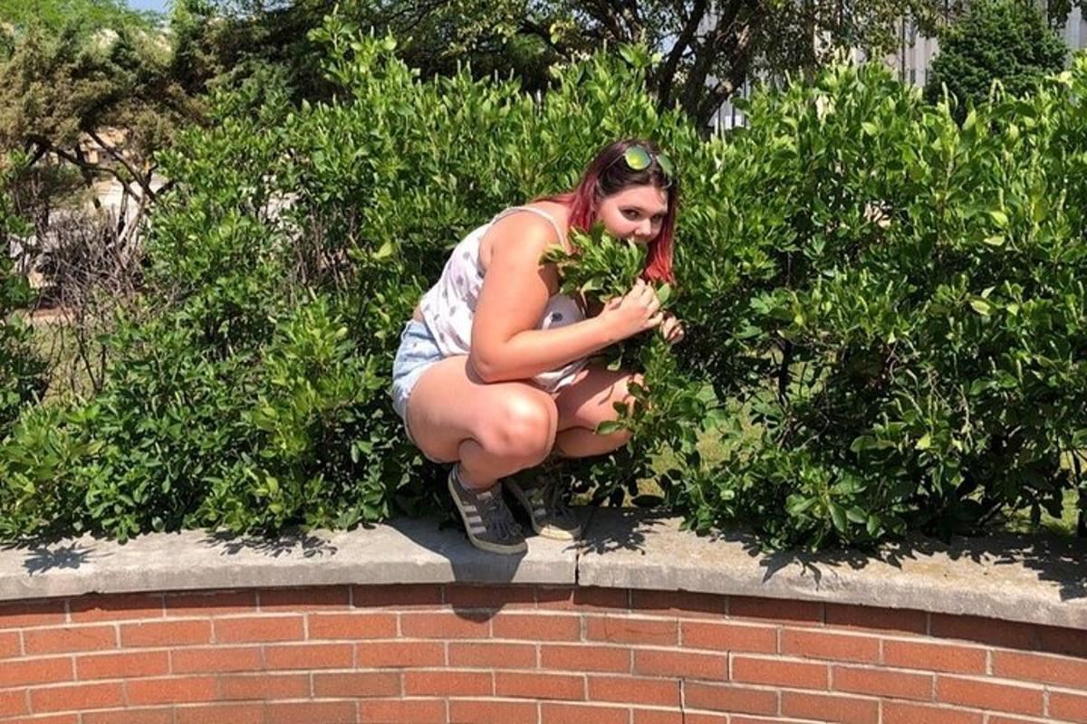 žena dřepí na cihlové zdi