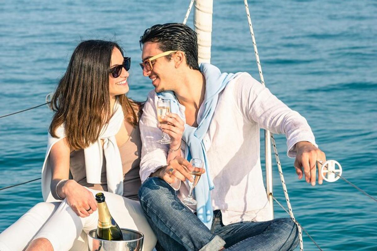 un home i una dona asseguts en un vaixell amb una ampolla de vi