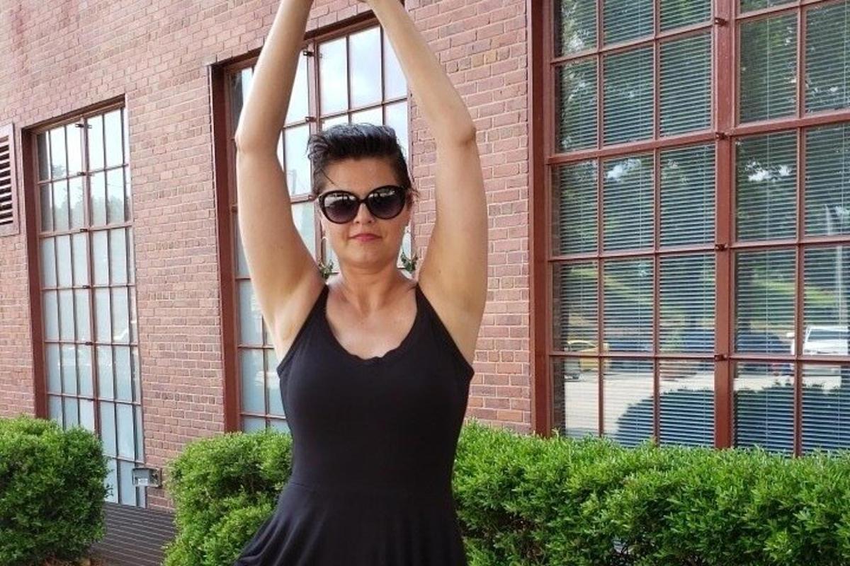 uma mulher de vestido preto com os braços no ar