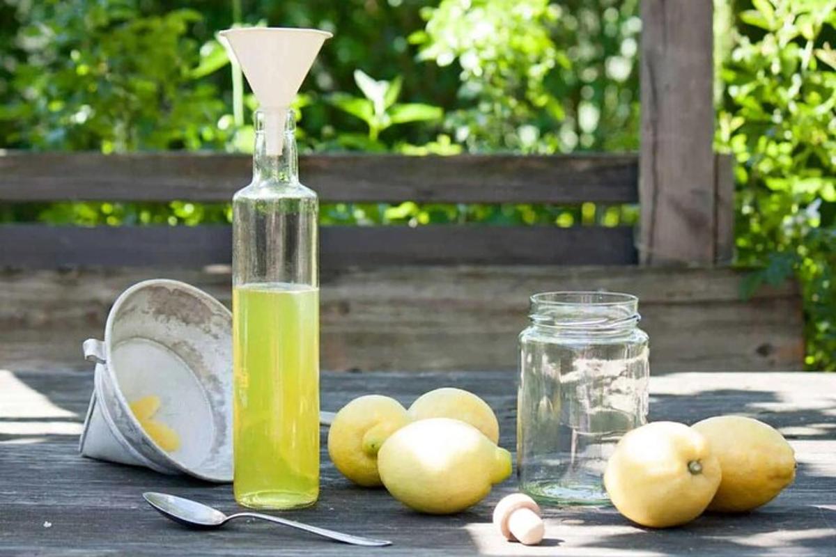 Una botella de líquido verde y algunas manzanas sobre una mesa.