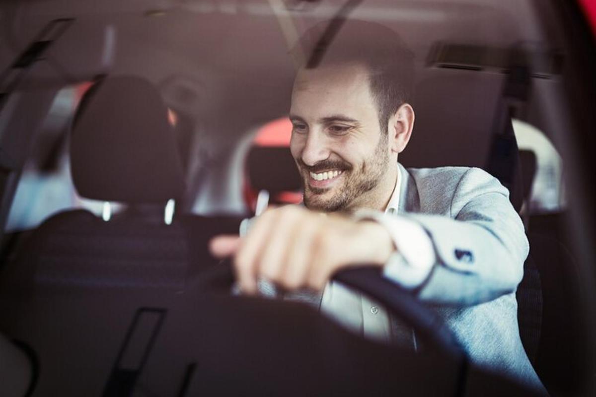 a man driving a car with his hand on the steering wheel