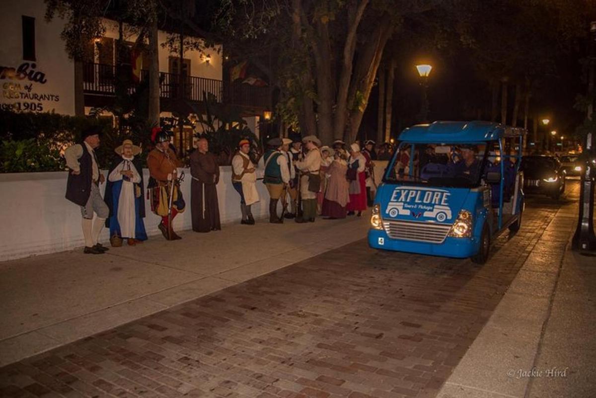 um grupo de pessoas em pé na calçada perto de um ônibus
