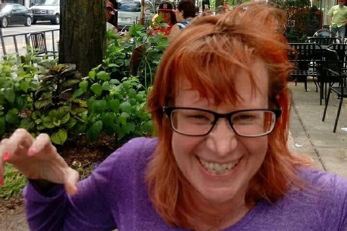 a woman with red hair and glasses is smiling