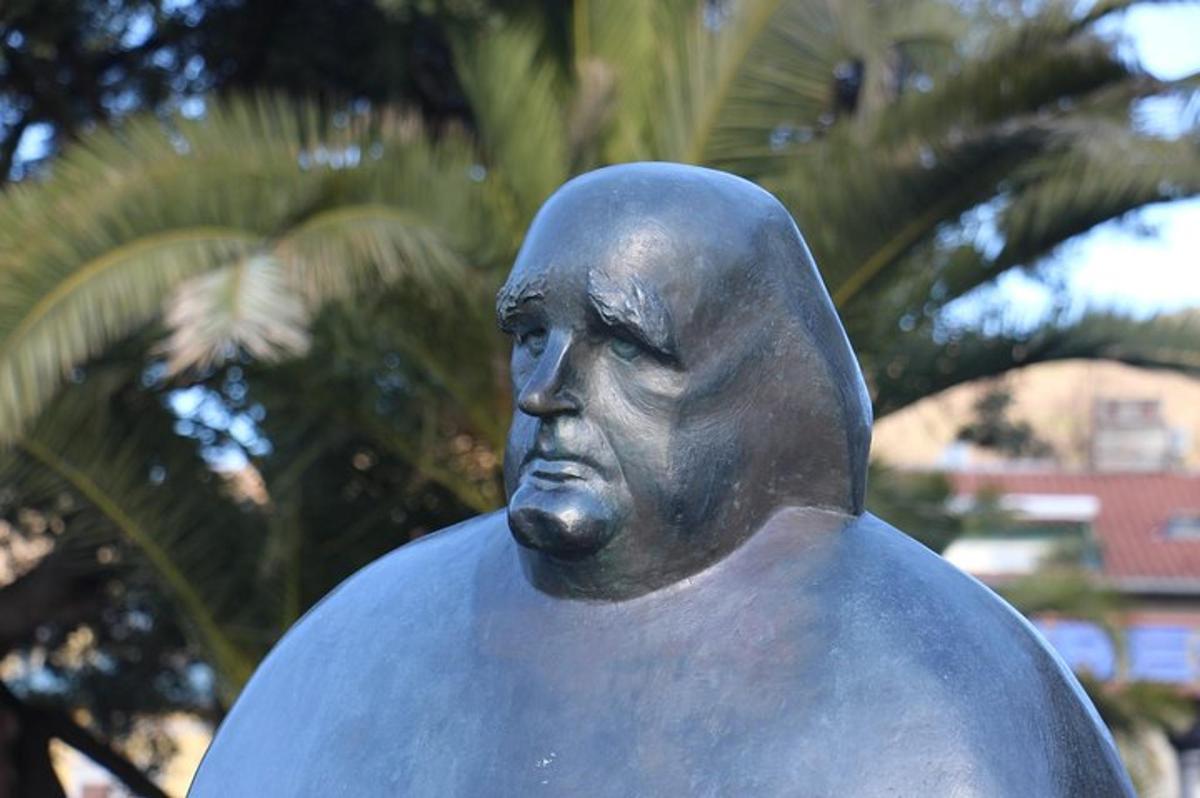 una estàtua d'un home assegut davant d'un arbre