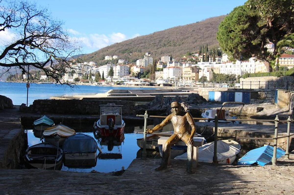 ένα άγαλμα ενός άνδρα που κάθεται σε μια αποβάθρα δίπλα σε βάρκες