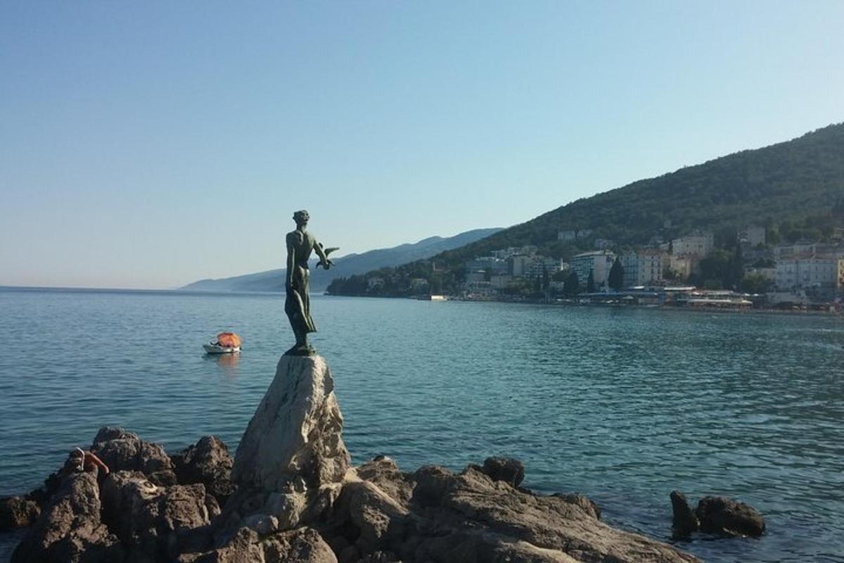 Una estatua de un hombre parado sobre una roca en el agua.