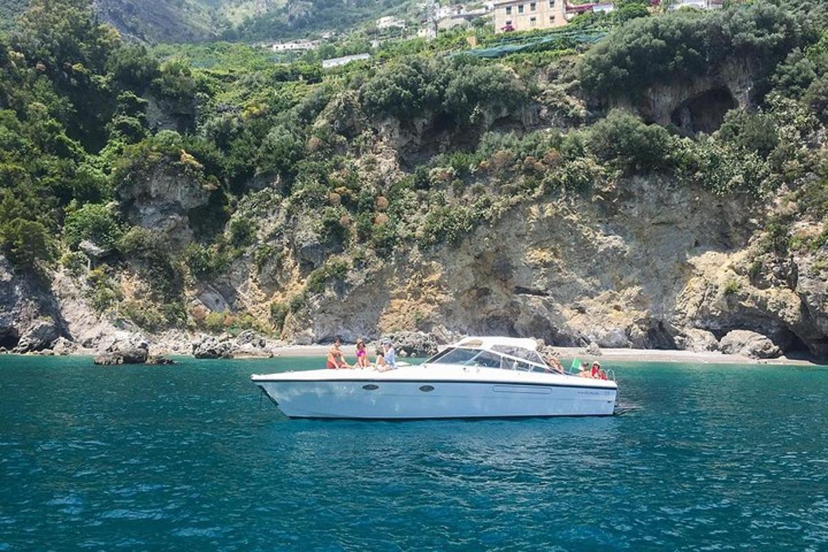 Un barco blanco en el agua junto a una montaña.