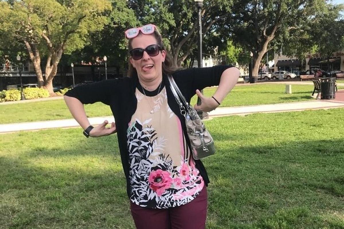 a woman standing in a park with her arms outstretched