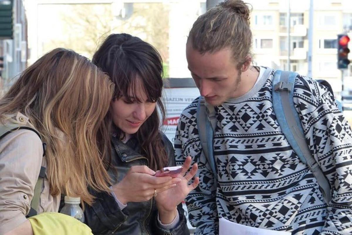 muž a dvě ženy se dívají na mobilní telefon