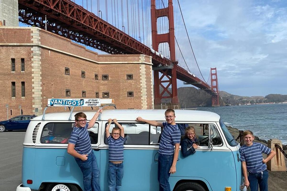 um grupo de pessoas em pé ao lado de uma van com a ponte Golden Gate