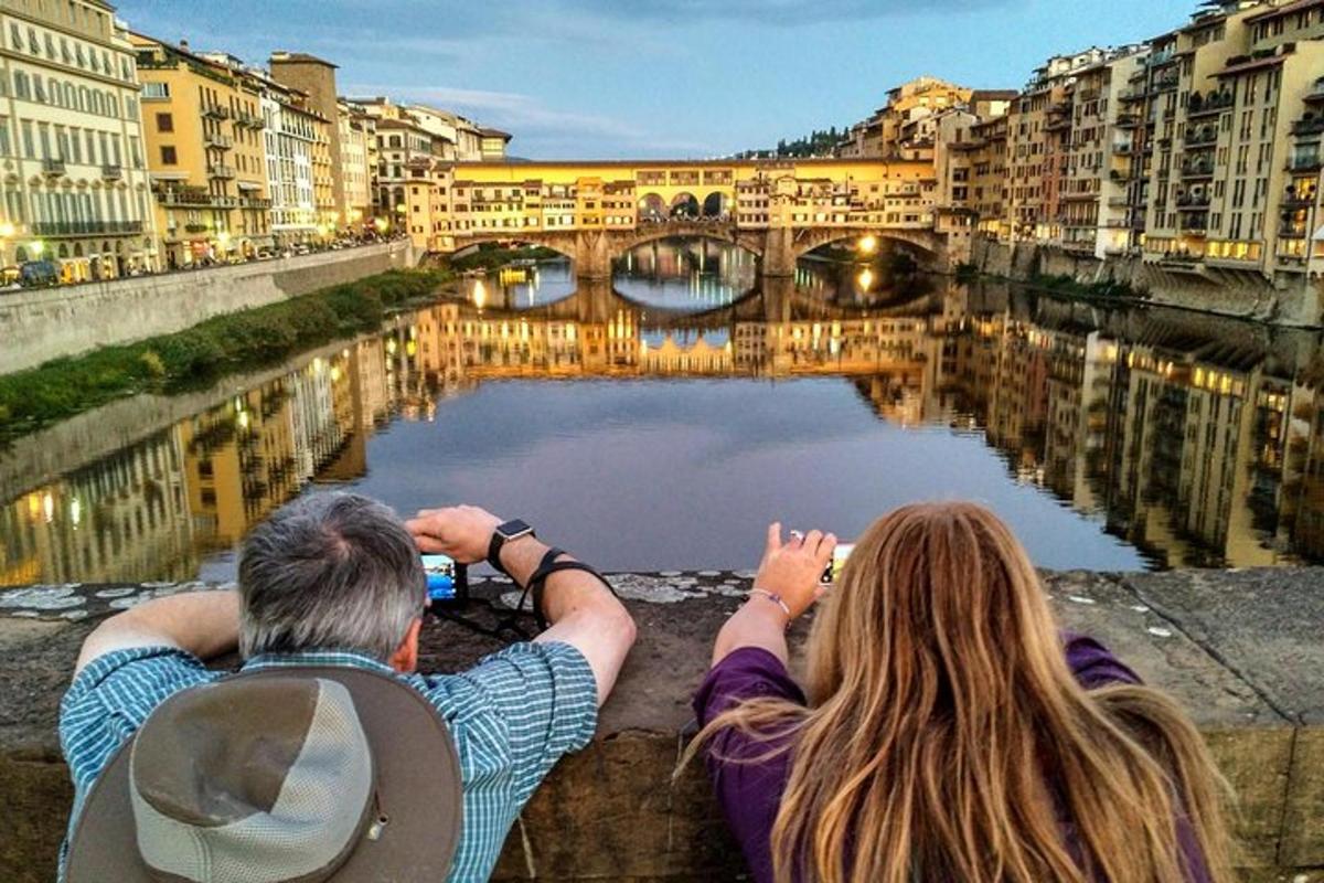 Un hombre y una mujer sentados en una cornisa mirando un río