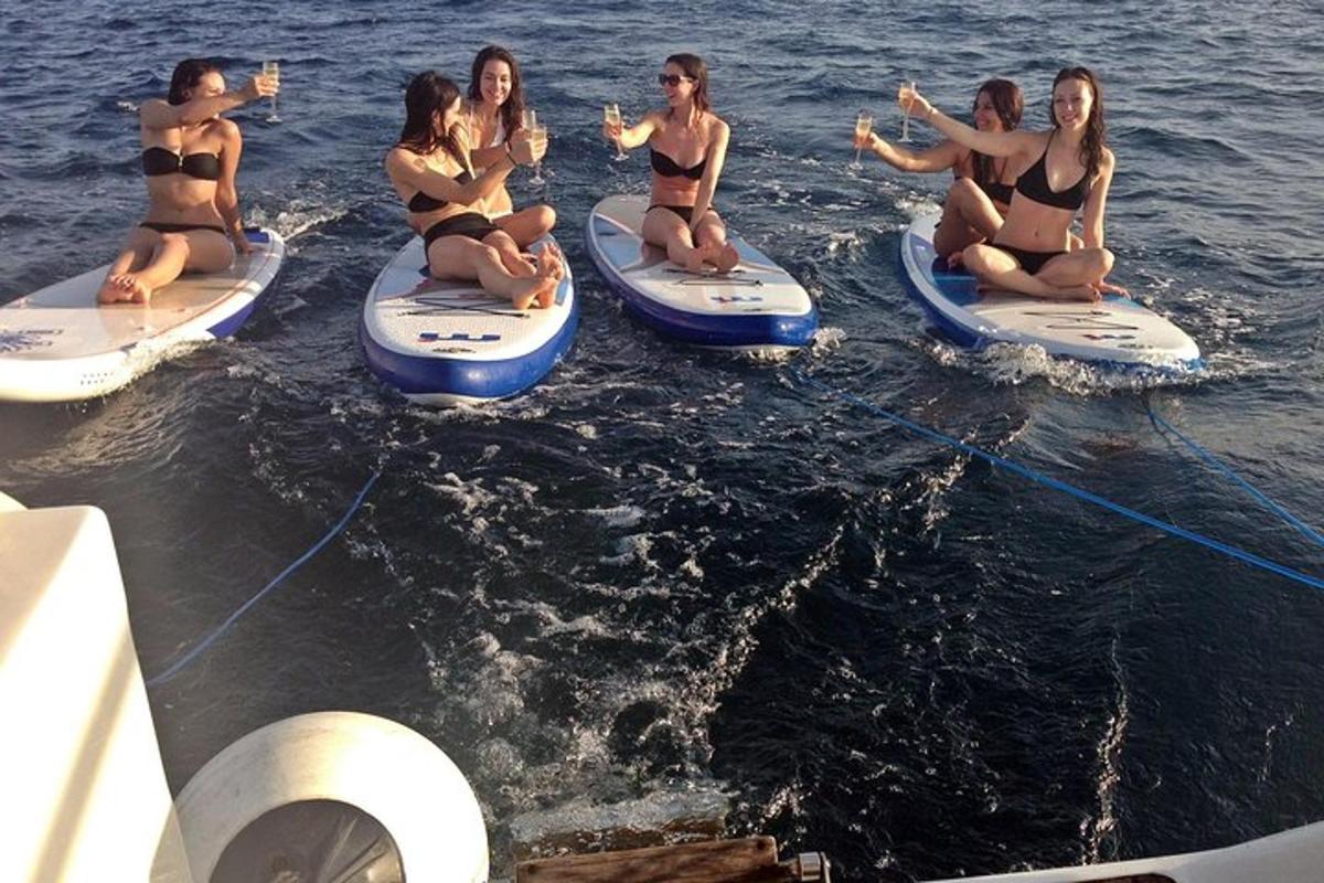 um grupo de mulheres em trajes de banho sentadas em pranchas de surfe na água