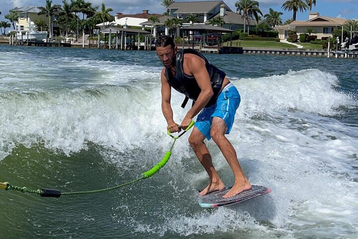 un bărbat călărind un val pe o placă de surf în apă