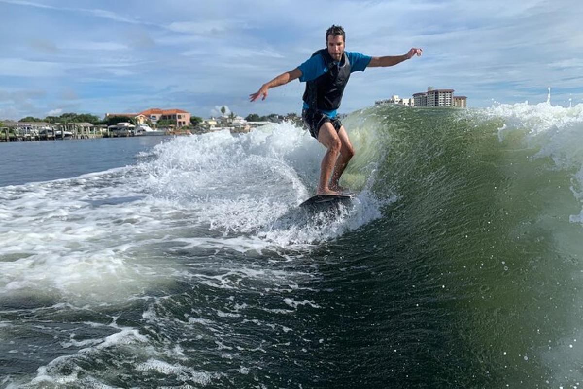 un home cavalcant una onada sobre una taula de surf a l'aigua