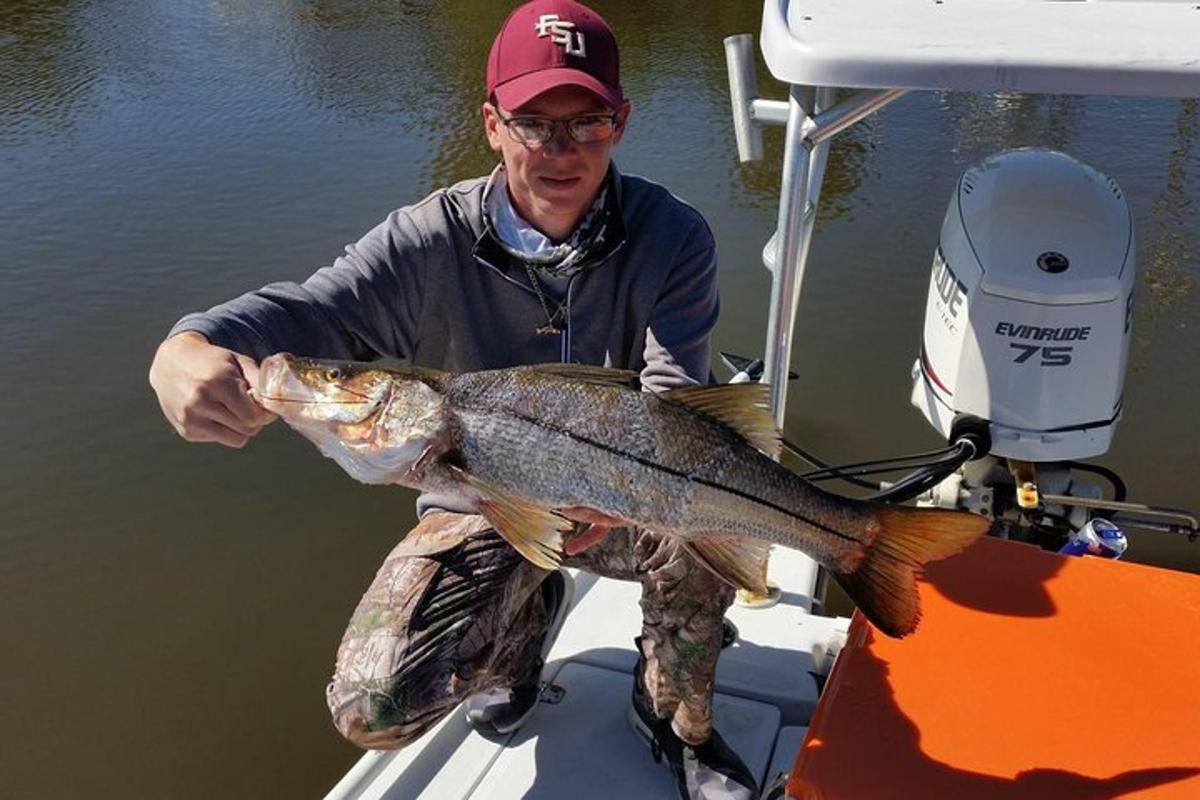 a man holding a large fish on a boat