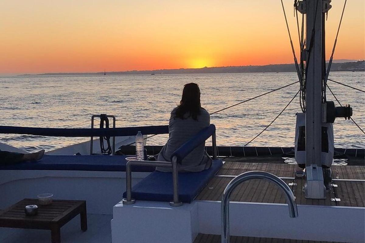 žena sedící na lodi a pozorující západ slunce