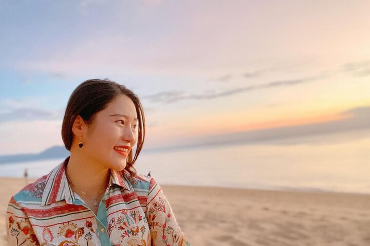 uma mulher em pé na praia ao pôr do sol