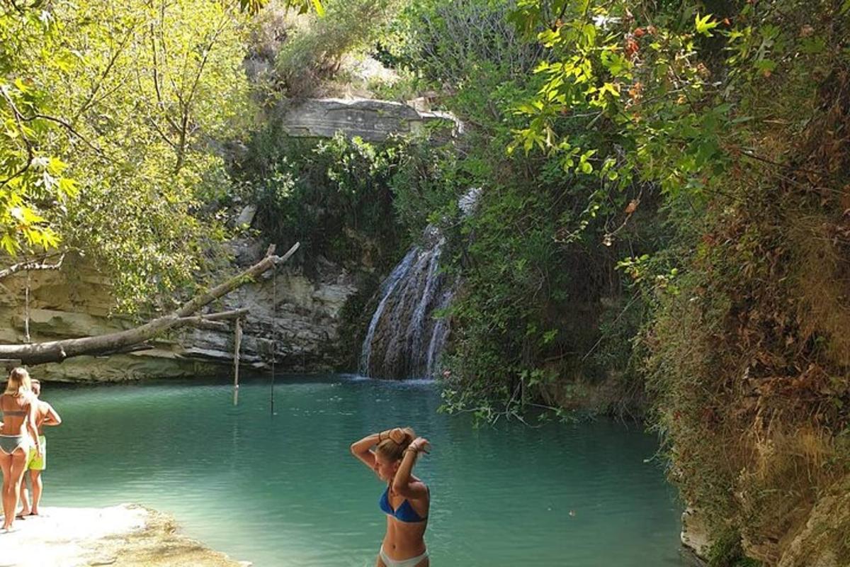 Μια γυναίκα που στέκεται σε μια λίμνη με νερό κοντά σε έναν καταρράκτη