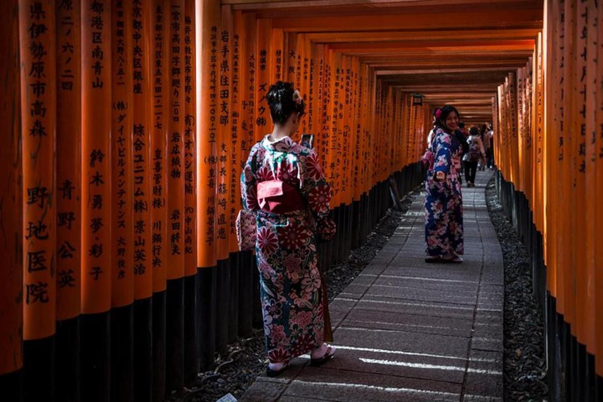 zwei Frauen in Kimonos gehen einen Flur mit orangefarbenen Wänden entlang