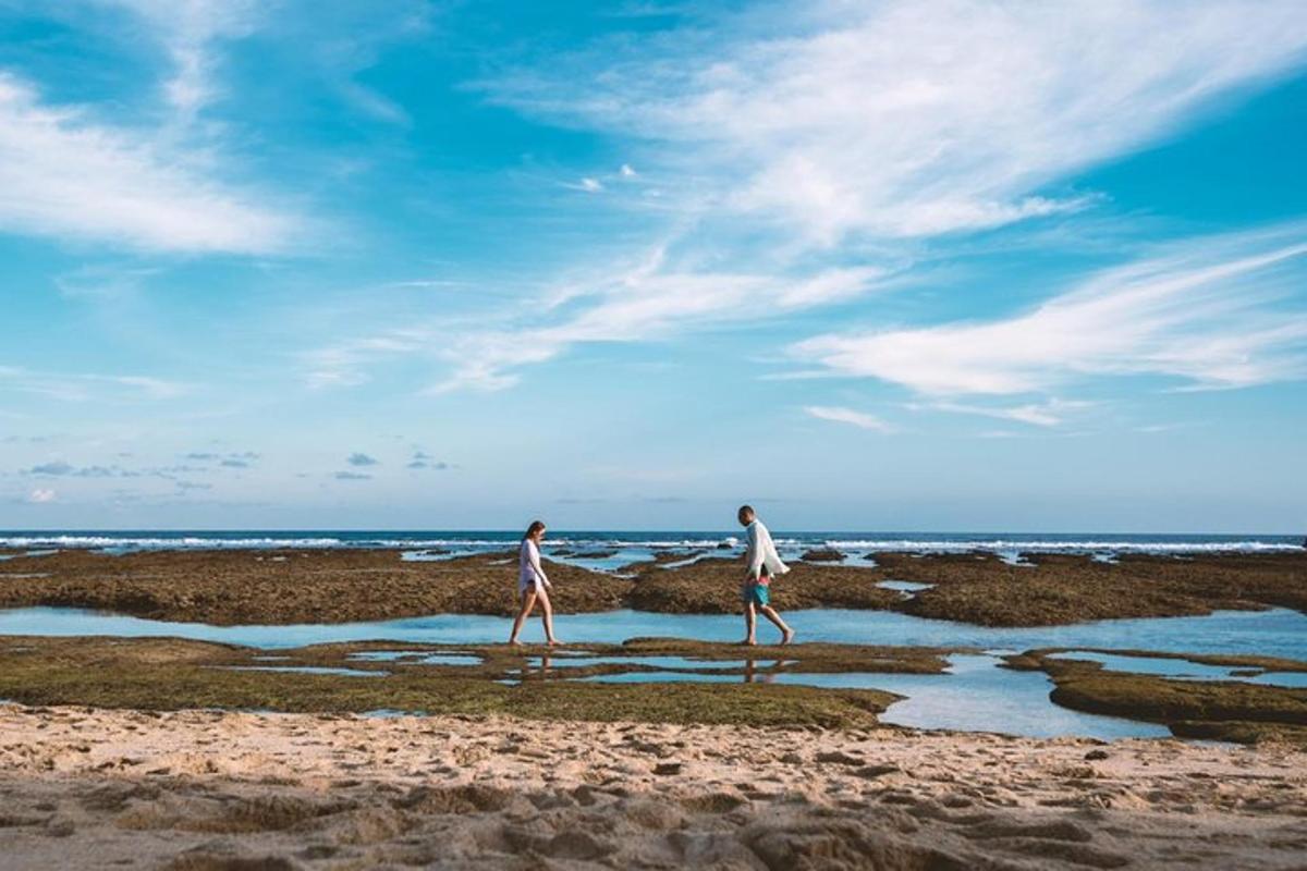 two people walking on the beach near the ocean