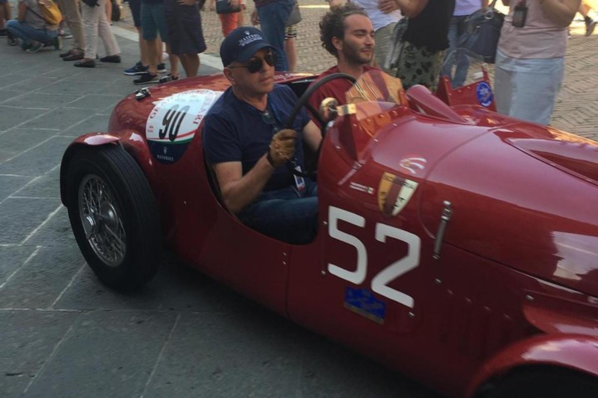 two men sitting in a red race car