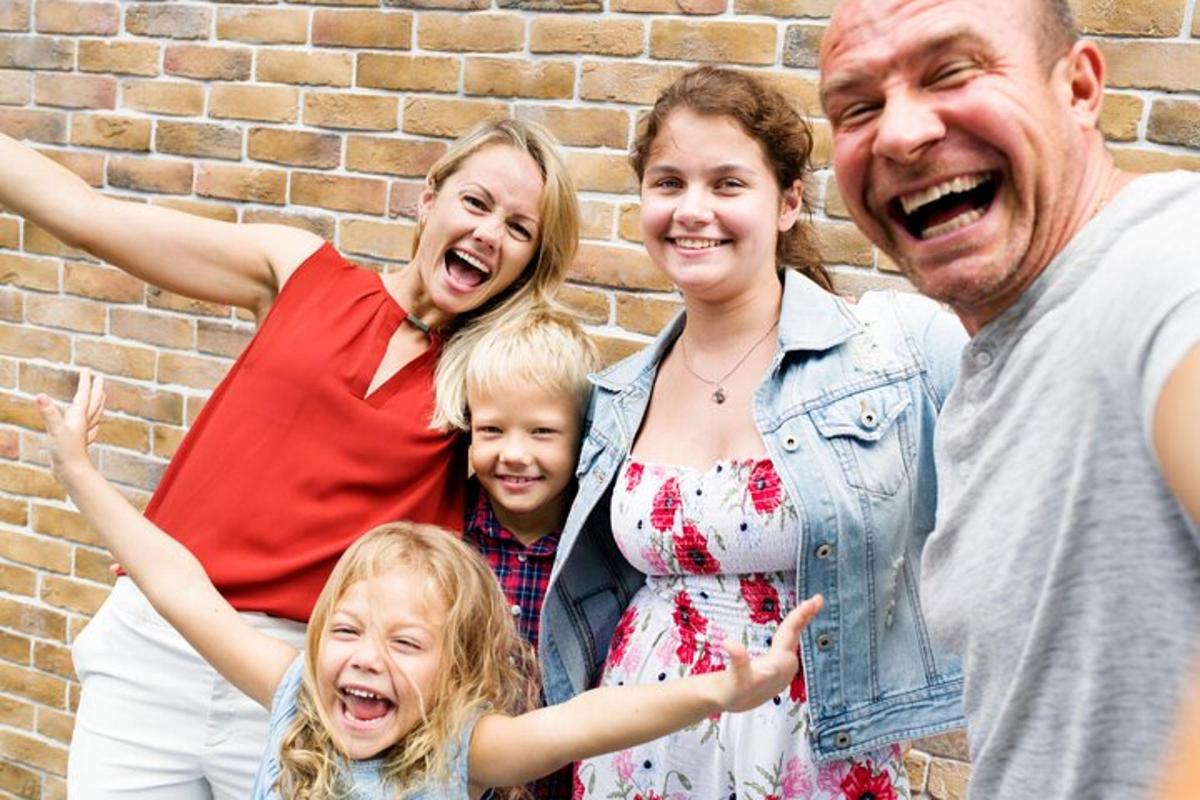 o familie care pozează pentru o fotografie în fața unui zid de cărămidă
