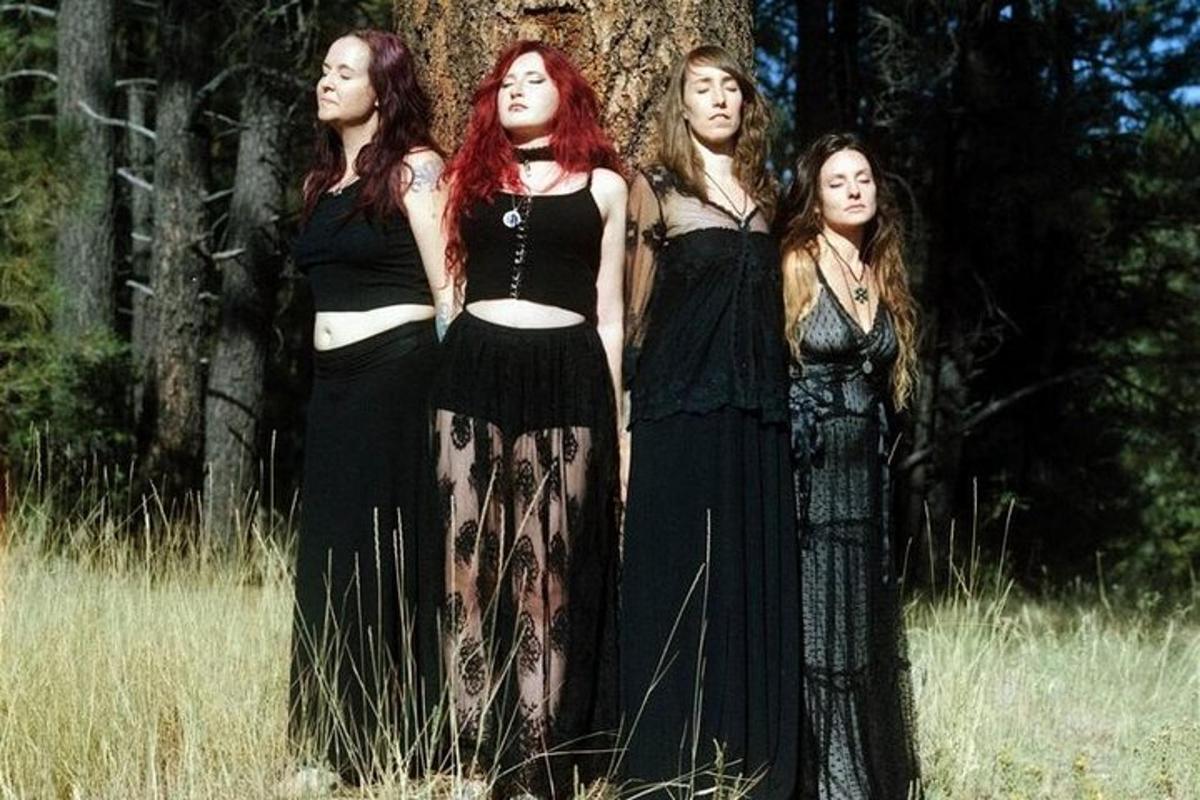 eine Gruppe von vier Frauen, die neben einem Baum stehen