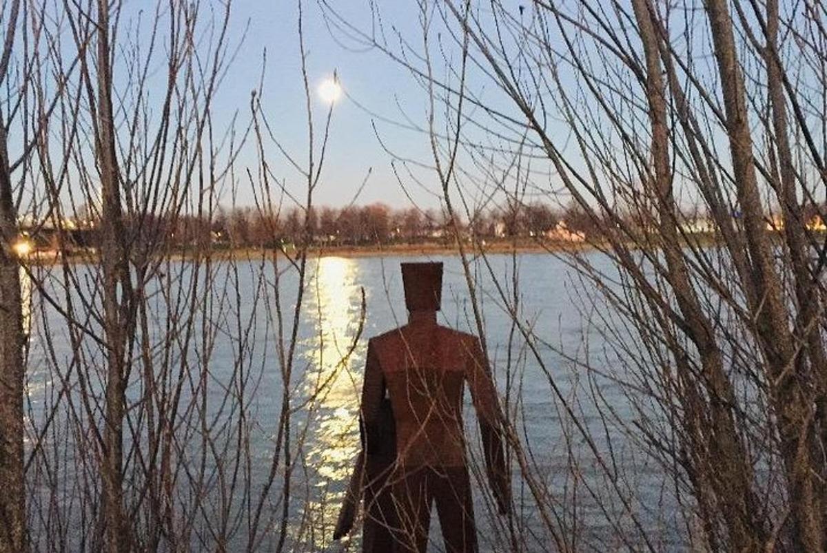 un uomo in piedi davanti a uno specchio d'acqua
