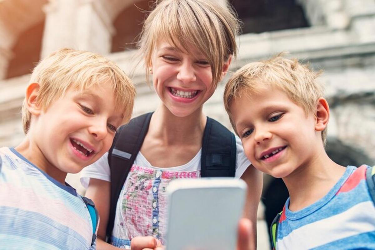 una dona i dos nens mirant un telèfon mòbil