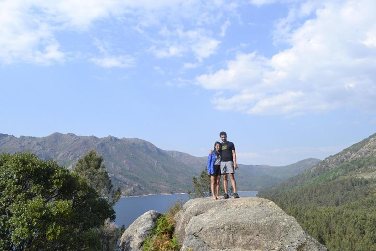 dva lidé stojící na vrcholu skály s výhledem na jezero