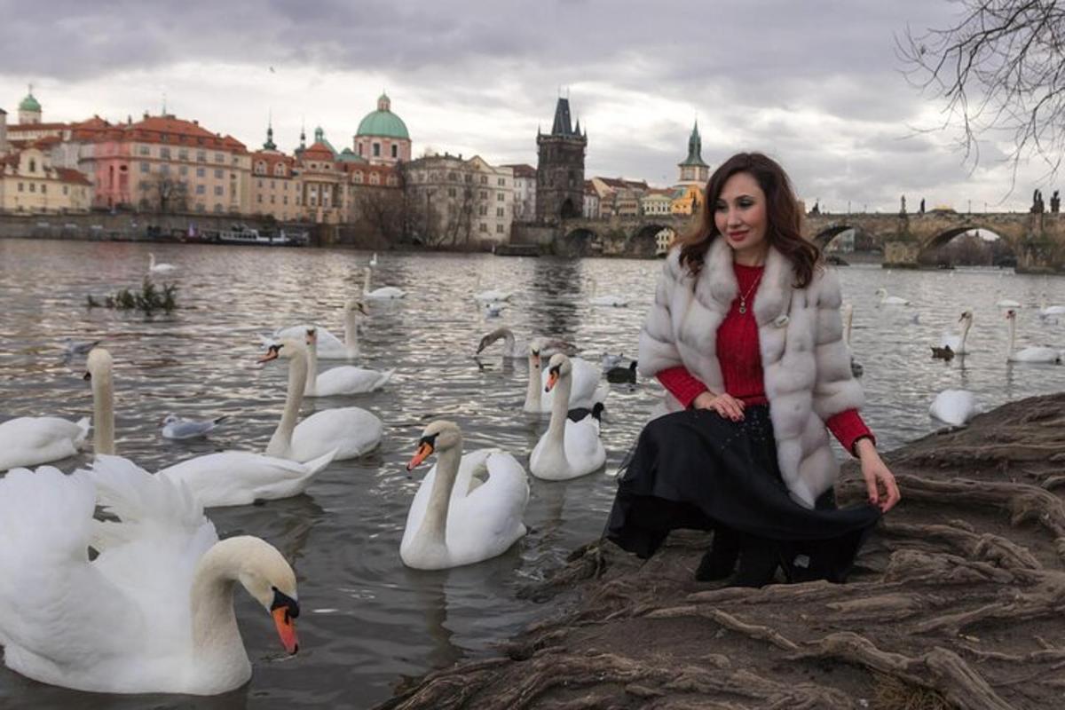 žena sedící vedle skupiny labutí ve vodě