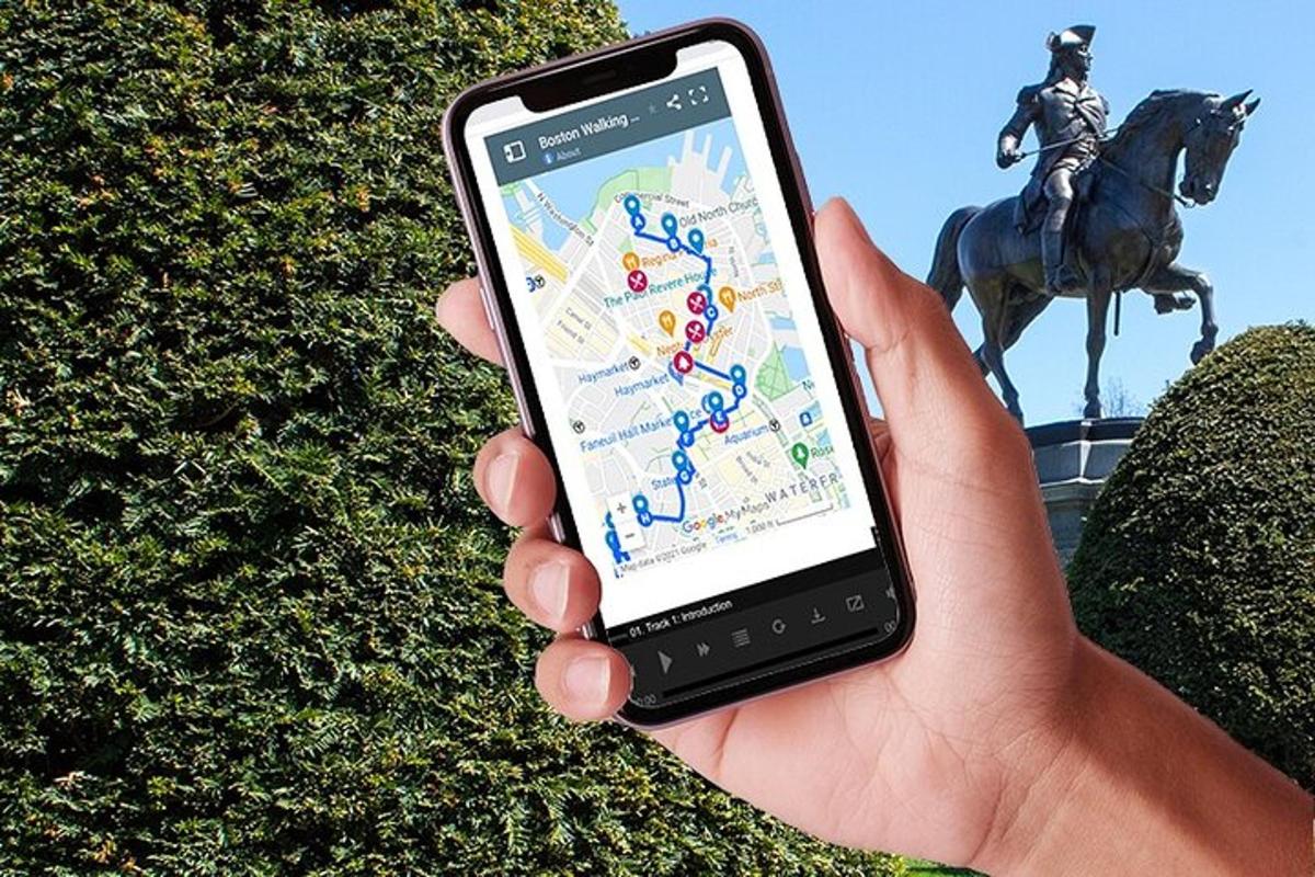 a person holding a cell phone in front of a statue