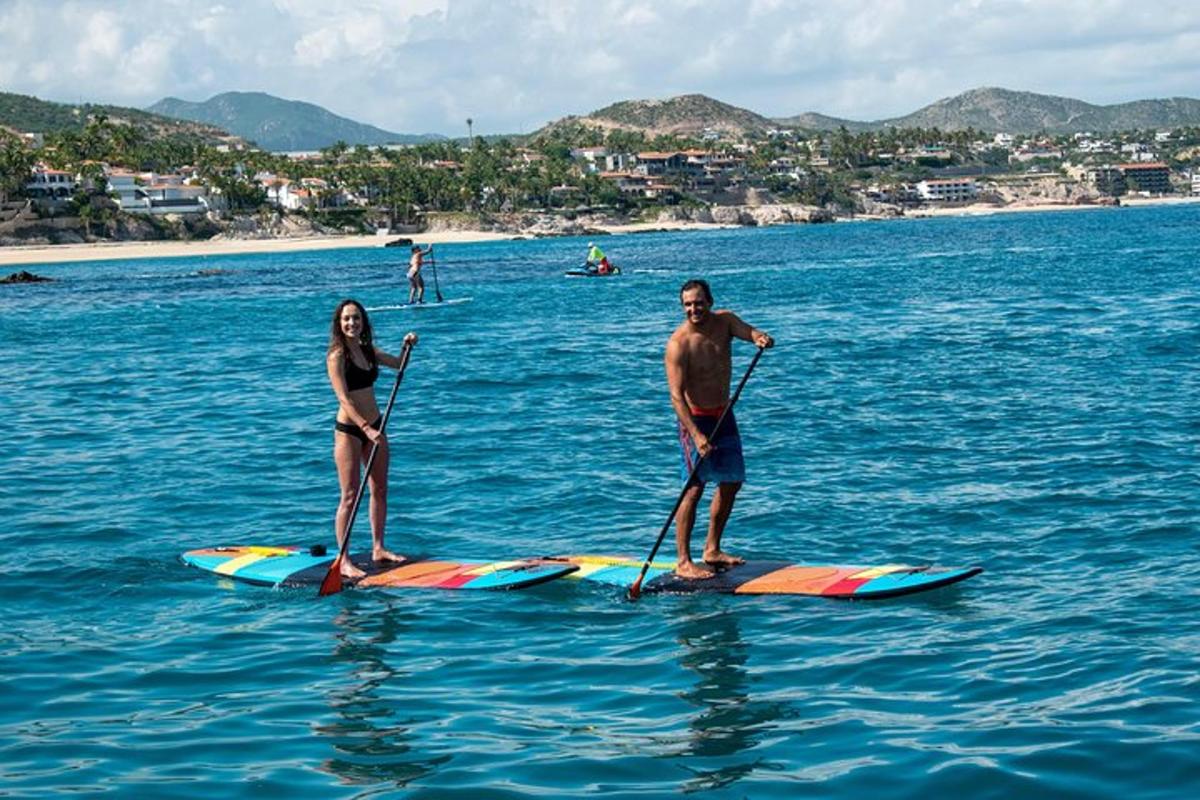 Dos personas están de pie sobre tablas de paddle surf en el agua.