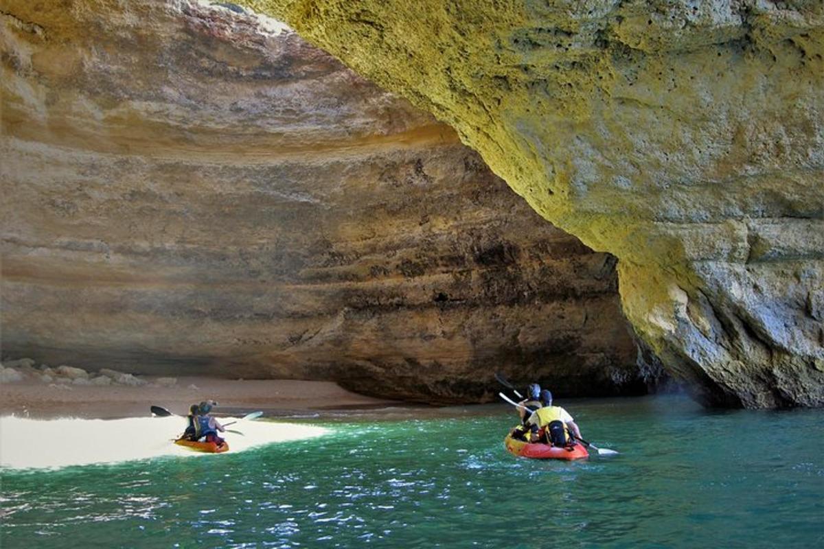 two people in kayaks in the water near a cave