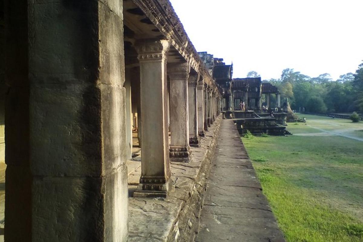 an ancient building with columns and a field of grass